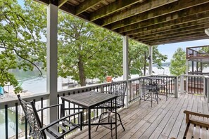 A covered outdoor deck with tables and chairs, overlooking a body of water and trees. - The Kelley's Lakefront Escape LOTO (Sunrise Beach)