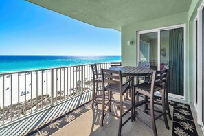 Varanda com mesa e cadeiras, vista para uma praia e oceano.