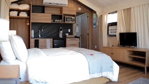 Une chambre avec un lit, une télévision, un four à micro-ondes et une petite kitchenette.