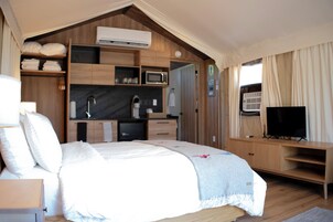 Un dormitorio con cama, televisor, microondas y una pequeña kitchenette.
