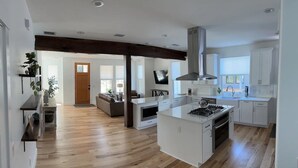 Eine moderne Küche mit Kochinsel, weißen Schränken und Holzboden.