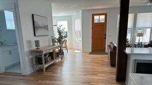 Ein geräumiger, gut beleuchteter Flur mit Holzboden, einer hölzernen Bank und einer Tür zu einem weiteren Zimmer.