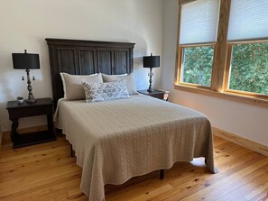 A bedroom with a bed, two nightstands, two lamps, and a window with blinds.