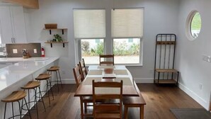 Uma cozinha moderna com uma mesa de jantar grande, banquetas de bar e um ventilador de teto.