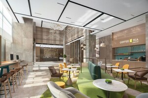 Interior de una cafetería moderna con zonas de estar, mostrador y un cartel con la carta a la vista.