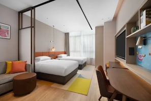 A modern hotel room with a large bed, a sofa, a desk, and a TV.