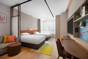 Quarto de hotel moderno com uma cama grande, um sofá, uma escrivaninha e uma televisão.