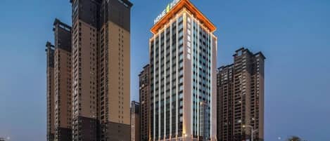A high-rise building with multiple floors, a prominent entrance, and a clear sky in the background.