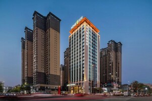 Un edificio de gran altura con varios pisos, una entrada destacada y un cielo despejado al fondo.
