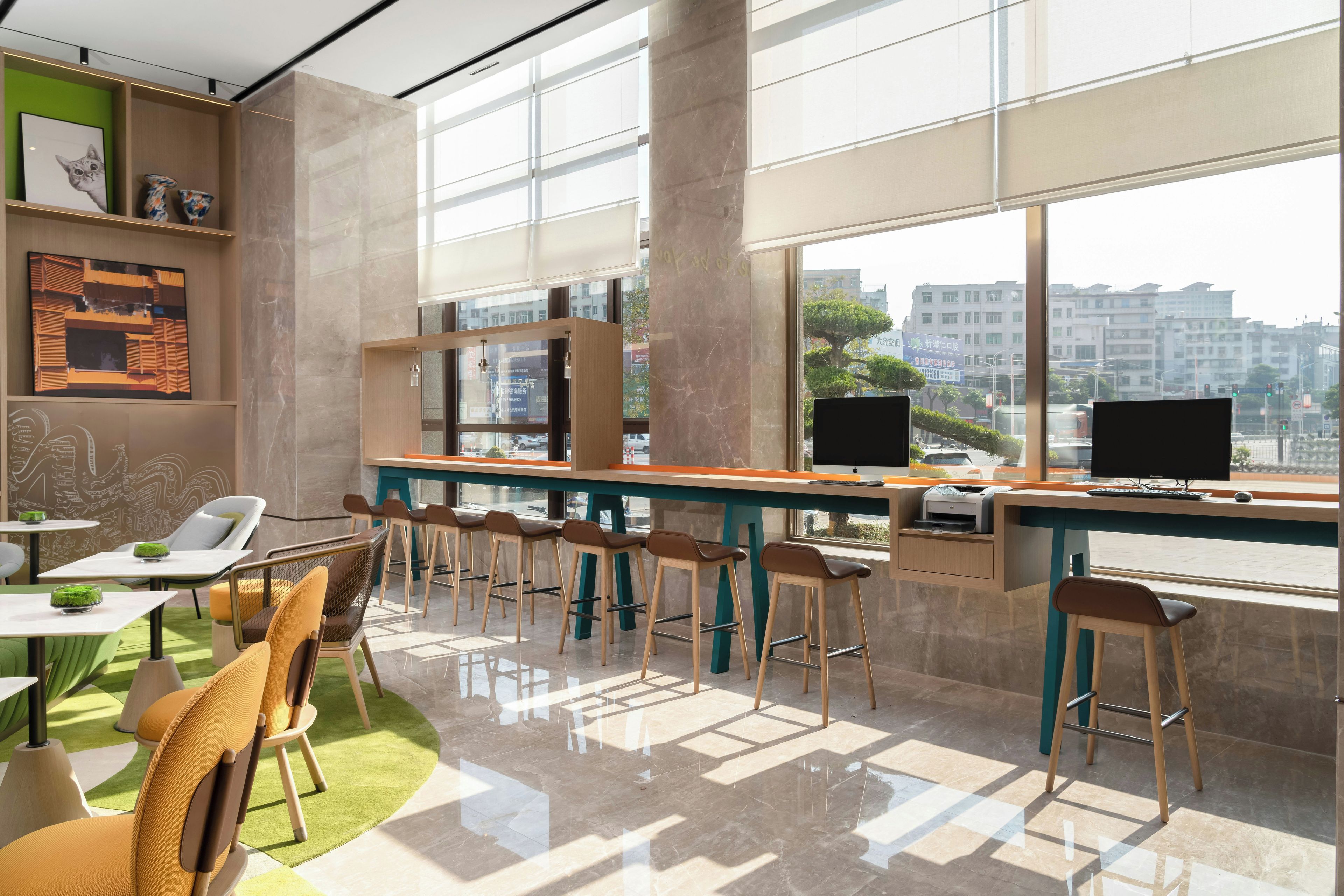 A modern office space with a long bar area, multiple seating options, and large windows offering a city view.