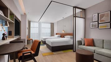 A modern hotel room with a bed, a sofa, a desk, and a dining area.