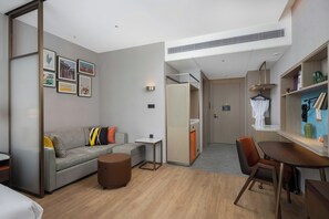 Una habitación de hotel moderna con sofá, una mesa de comedor y una pequeña cocina.