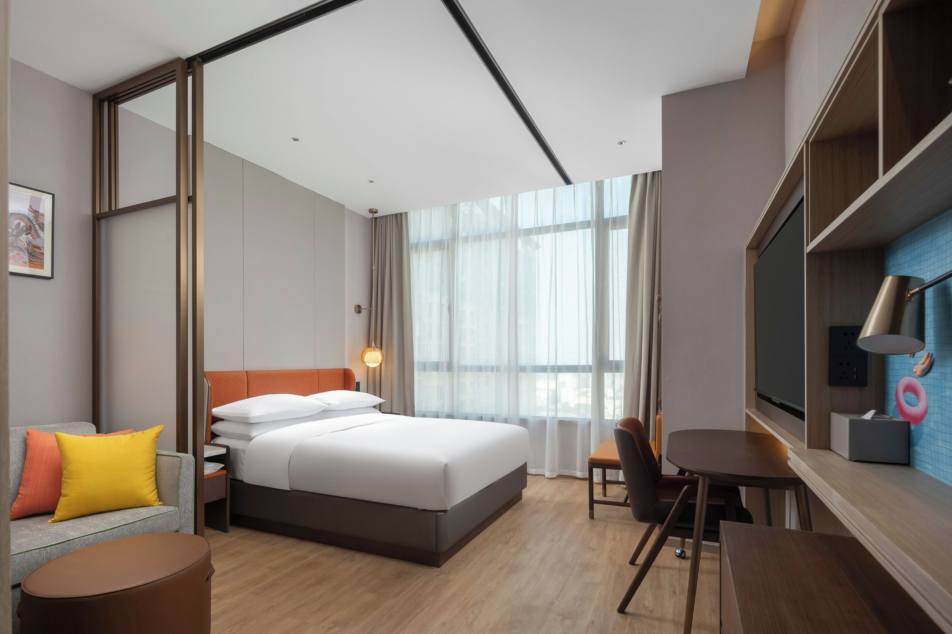 A modern hotel room with a large bed, a desk, a chair, and a television.