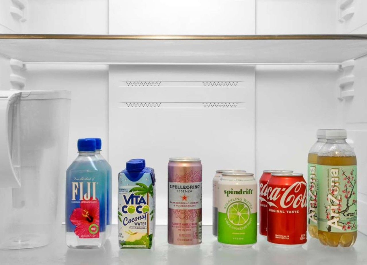 Ein Kühlschrank mit verschiedenen Getränken, darunter Fiji Wasser, Vita Coco Kokoswasser, Pellegrino, Spindrift, Coca-Cola und Arizona.