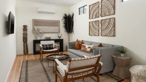 Un salon avec un canapé gris, une chaise en bois, une table basse et une cheminée.