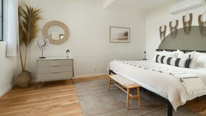 Ein Schlafzimmer mit Bett, Nachttisch, Kommode und einem großen Spiegel.