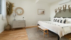 Un dormitorio con cama, mesita de noche, cómoda y un espejo grande.