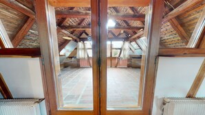 An attic room with a sloped wooden ceiling, a large wooden door, and a view of a brick floor and a bed. - manala 2 gite a turckheim (Turckheim)