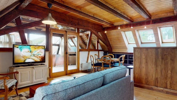 A cozy room with a wooden ceiling, a television, a sofa, and a dining area with chairs and a table. - manala 2 gite a turckheim (Turckheim)