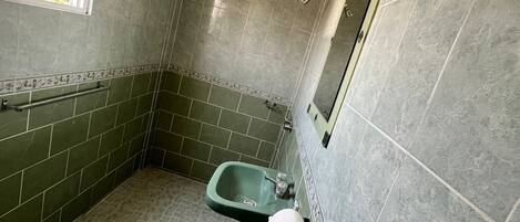 A bathroom with a green sink, a toilet, and a shower.