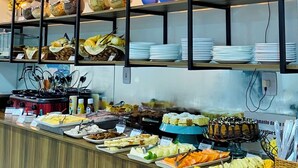 A buffet setup with various food items and utensils. - Pousada Safari (Penha)