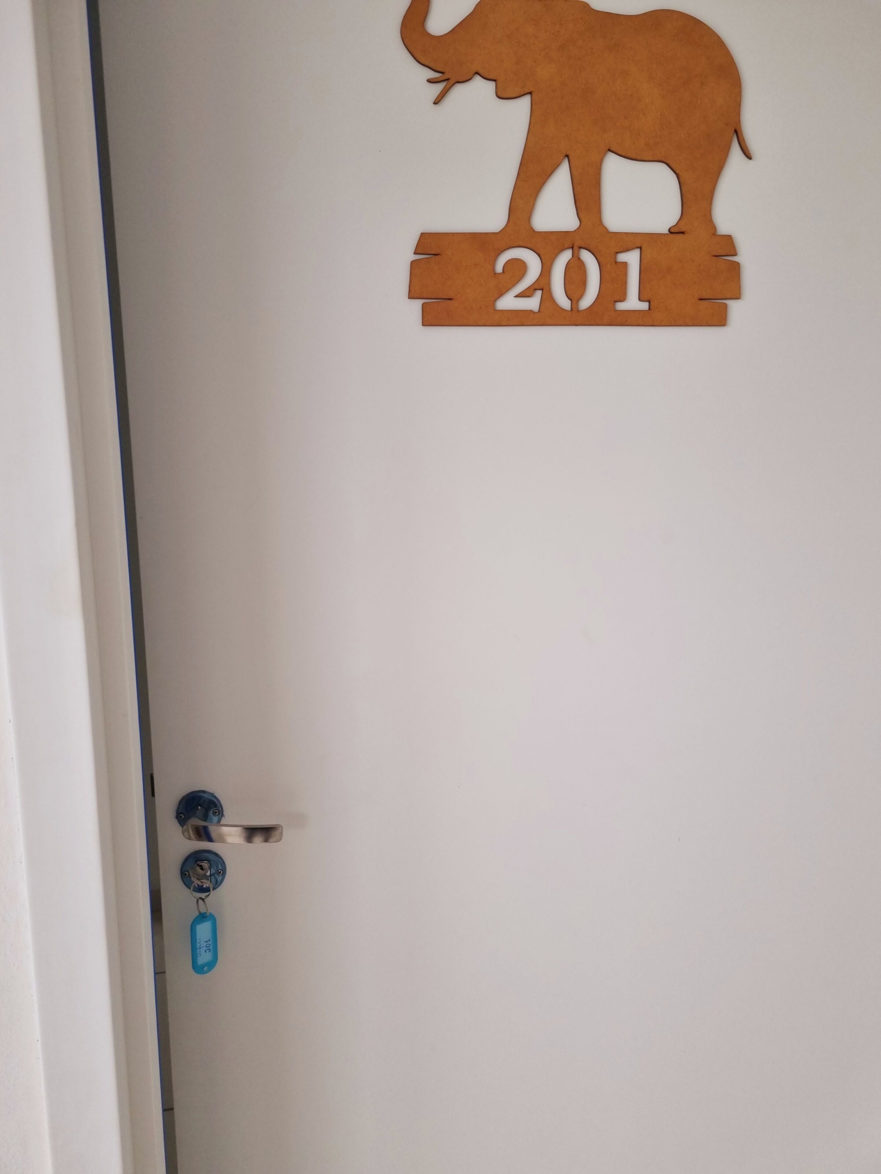 A door with a wooden elephant silhouette and the number 201.