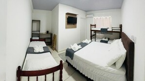 A dormitory room with two single beds, a desk, a chair, a TV, and a window with curtains. - Pousada Safari (Penha)