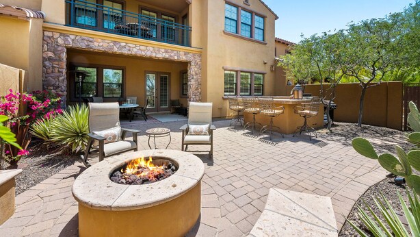 A patio with a fire pit, outdoor furniture, and a stone fireplace.