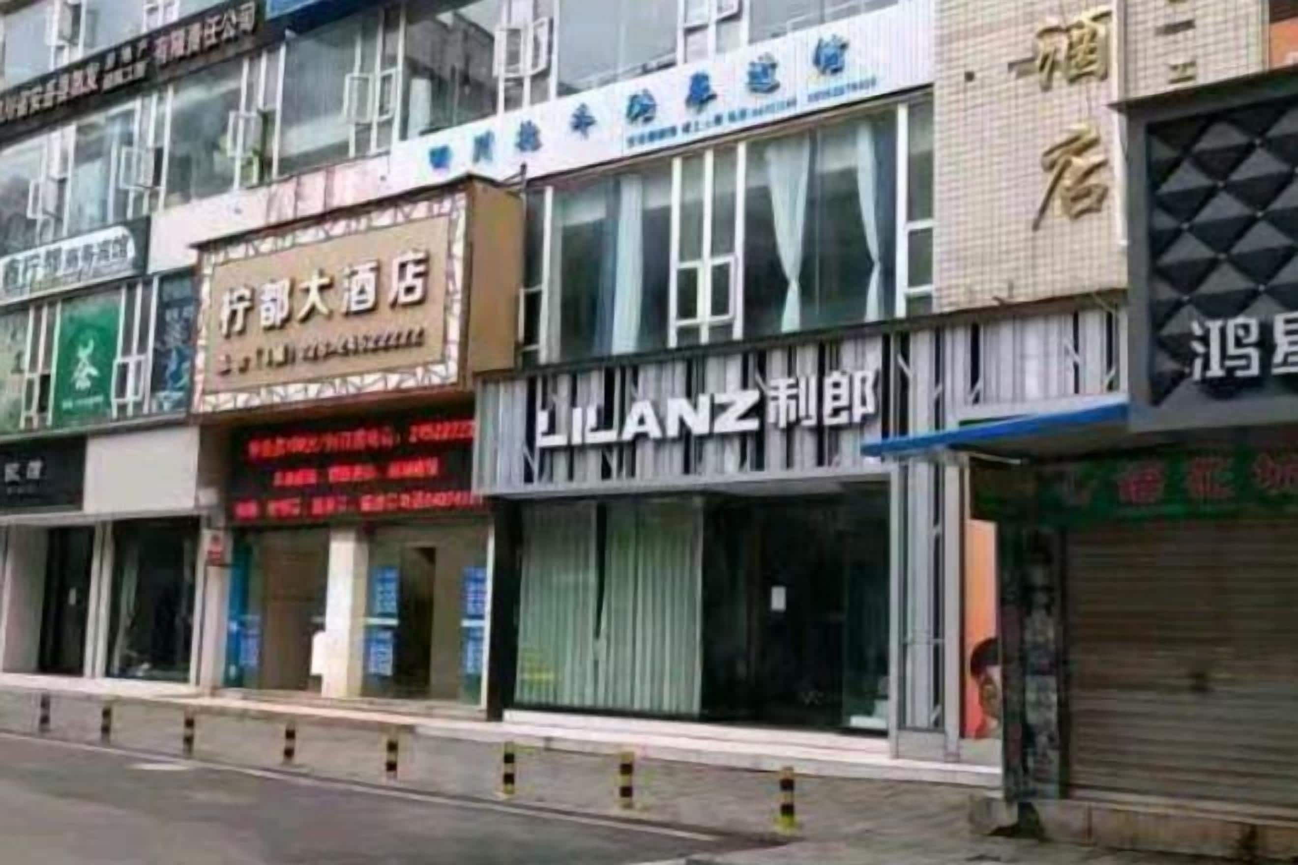 A row of storefronts with signage in a foreign language, some with closed shutters.