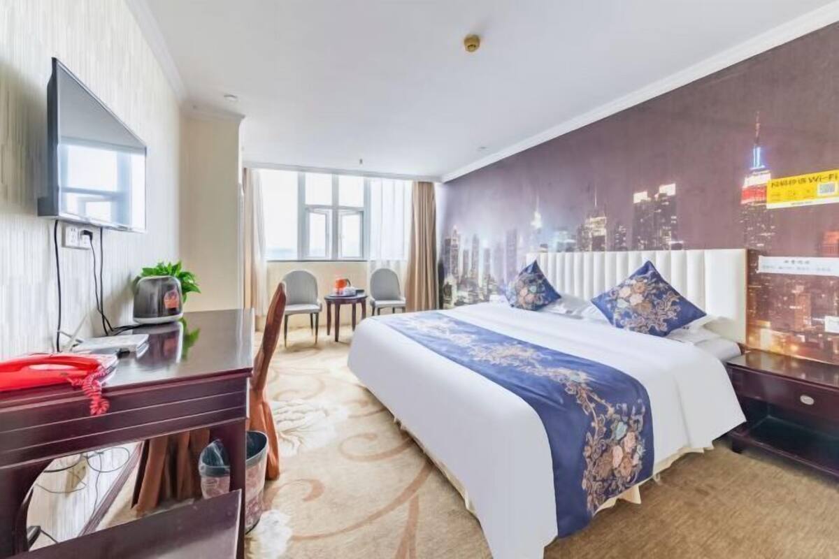 Relax in a spacious room with a large bed, flat-screen TV, and city view.
