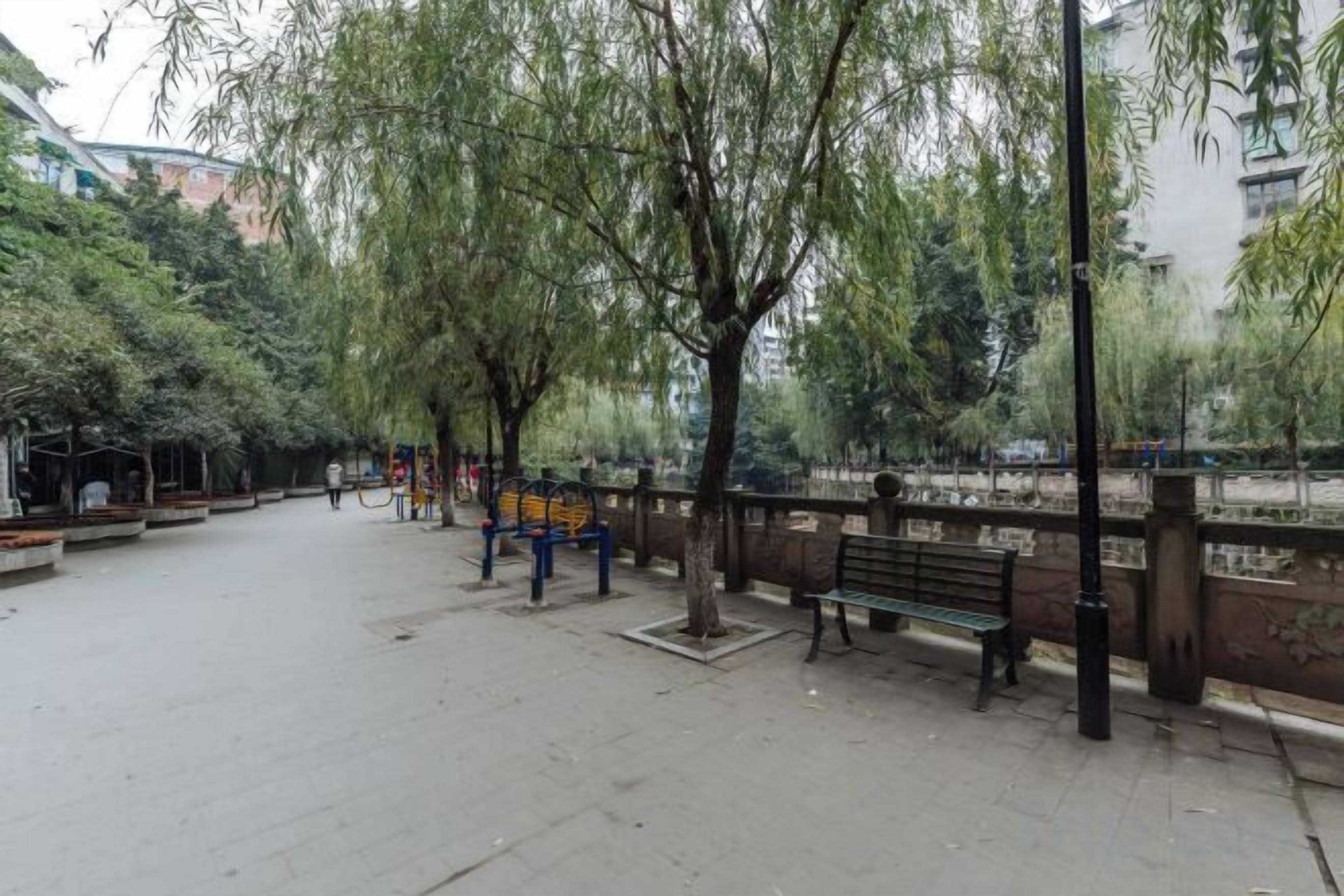 A park with benches, trees, and a paved walkway.