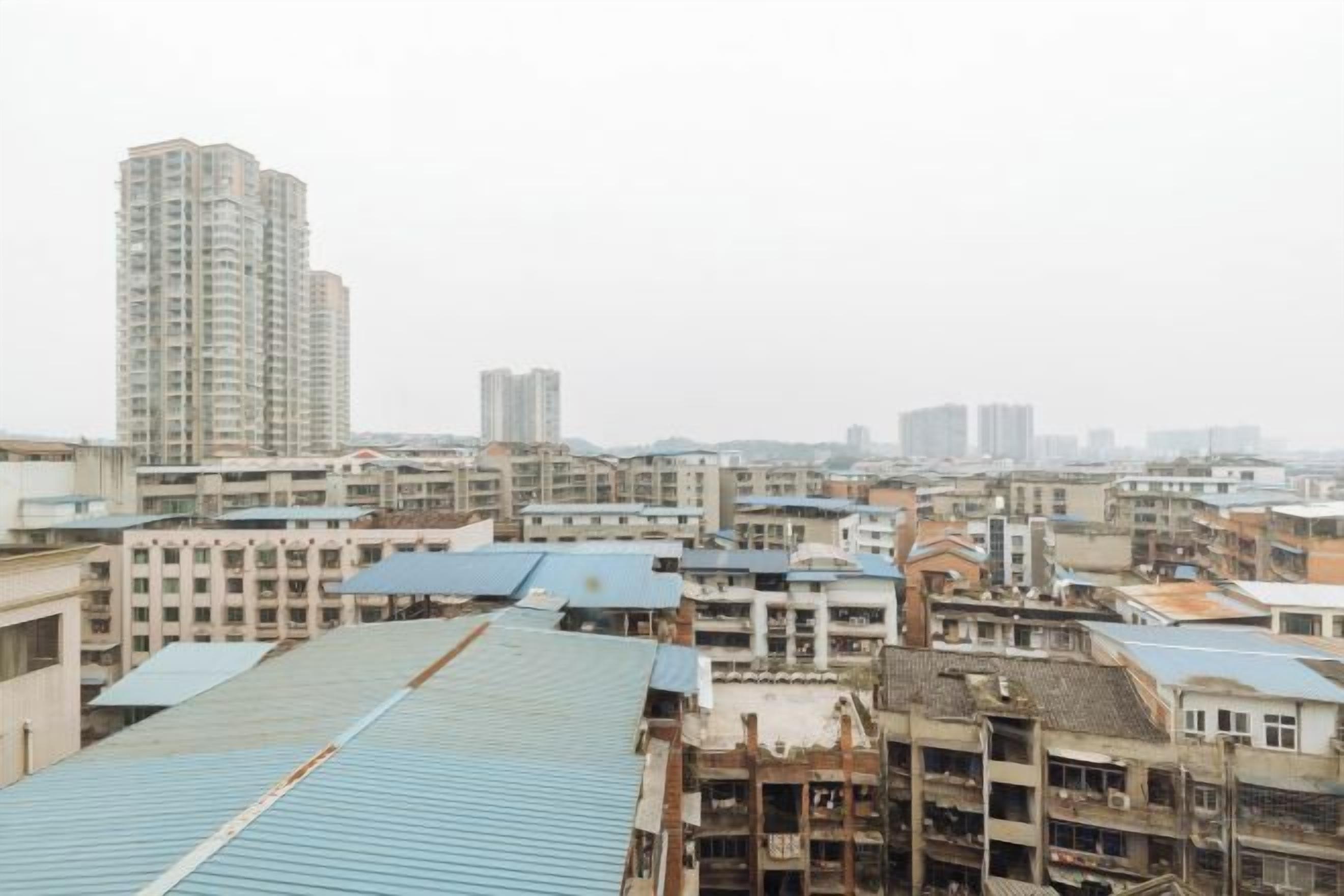 A cityscape with multiple buildings, including a tall residential tower and various smaller structures.