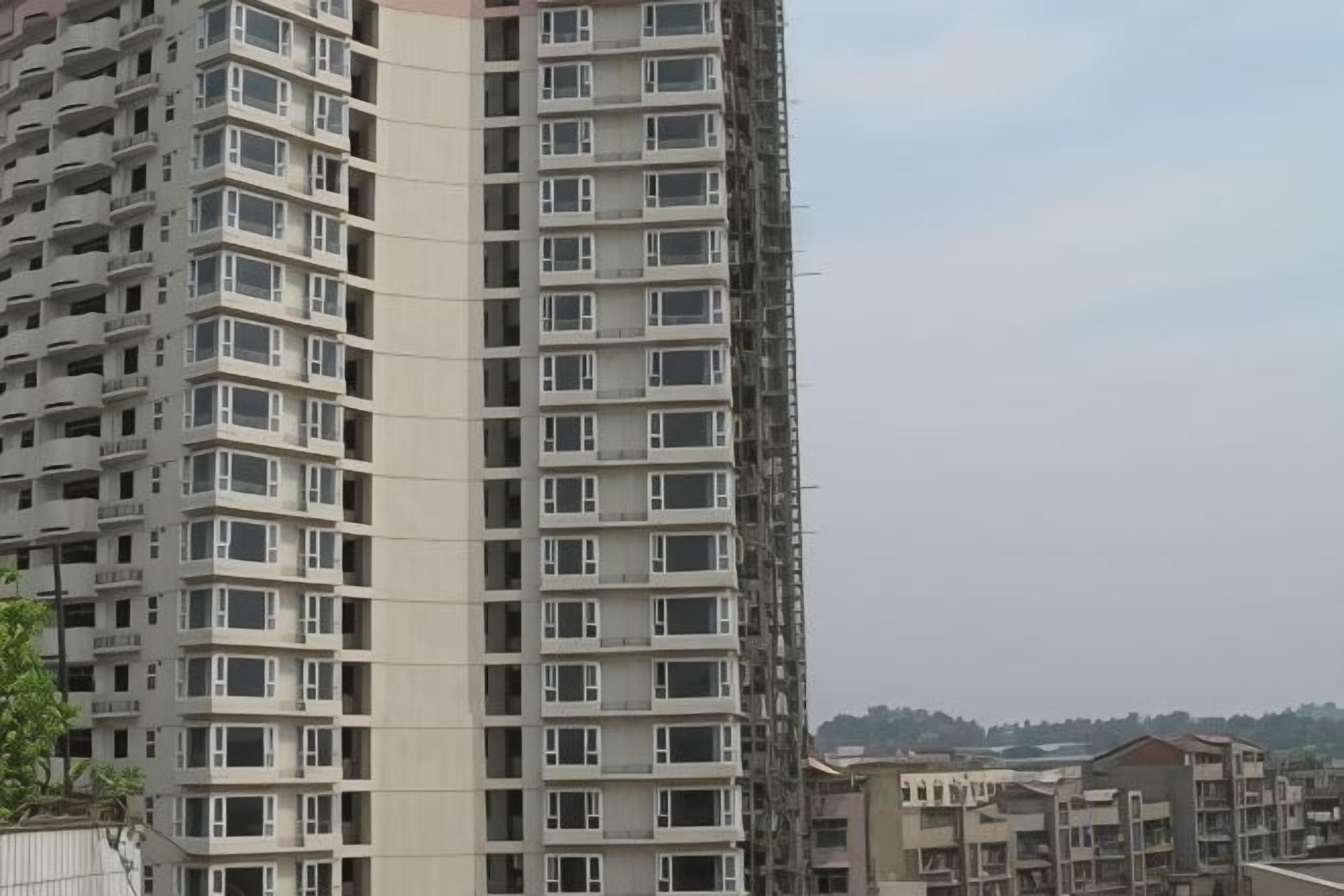 A high-rise building with multiple floors and balconies, surrounded by other buildings.