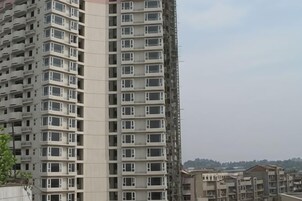 Un edificio de gran altura con varios pisos y balcones, rodeado de otros edificios.