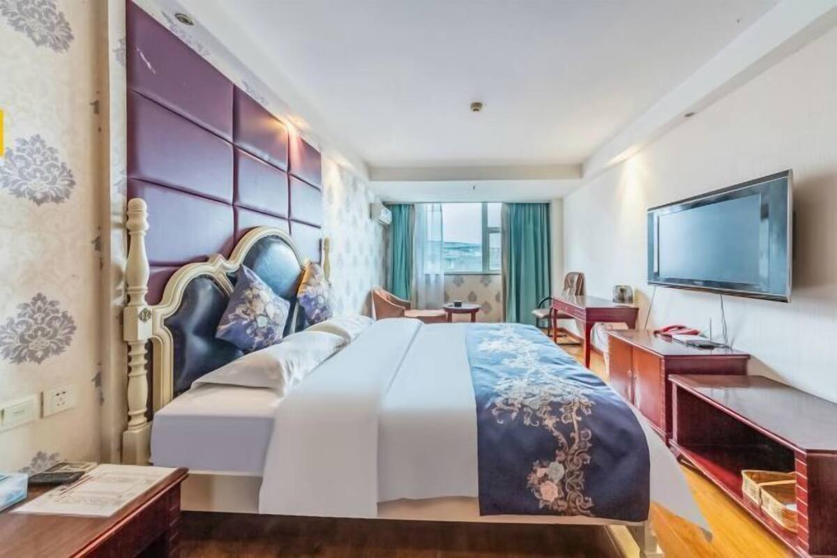 Relax in this stylish room featuring a large bed with a decorative headboard, flat-screen TV, and a desk for work or leisure.