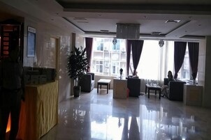 Un hall de hotel con una recepción, zona de estar y grandes ventanales.