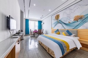 A modern hotel room with a large bed, a desk with a computer, a TV, and a painting on the wall. - Ningdu Hotel (Anyue)
