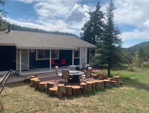 Relax in a serene natural setting, surrounded by trees and hills, with a covered patio featuring a circular seating area.
