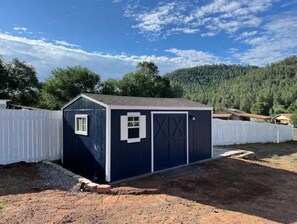 Situated in a peaceful rural setting, this charming outbuilding features a small window and a cross-shaped garage door.