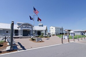 A town hall with a sign reading "Town of Kure Beach," a flagpole with the American flag, and a clear blue sky.