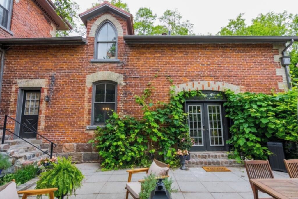 A brick building with a front door, a window, and a staircase leading to the entrance.