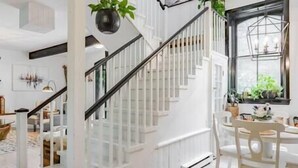 Un escalier avec des rampes blanches et un plancher en bois menant à un coin repas équipé d’une table et de chaises.