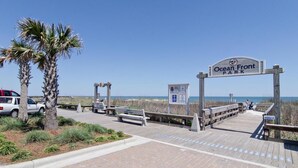 Ein Holzsteg führt zum Ocean Front Park, mit Bänken und einem Schild.