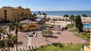 A resort with a pool, palm trees, and a beach view.