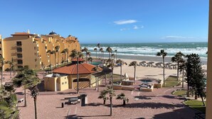A hotel with a pool area, beach access, and palm trees.