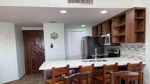 A kitchen with a central island, wooden cabinets, a microwave, and a sink.