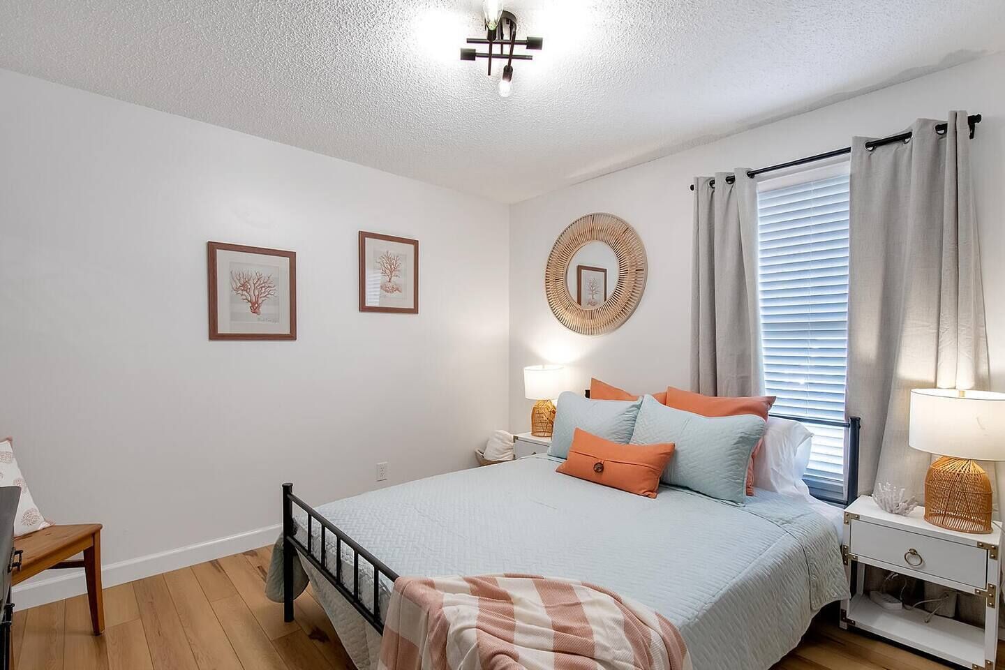 A bedroom with a bed, bedside tables, a lamp, a chair, and framed pictures on the wall.