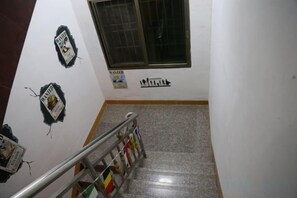 Eine Treppe mit Handläufen, einem Fenster und Wanddekorationen, darunter ein 'WANTED'-Poster.