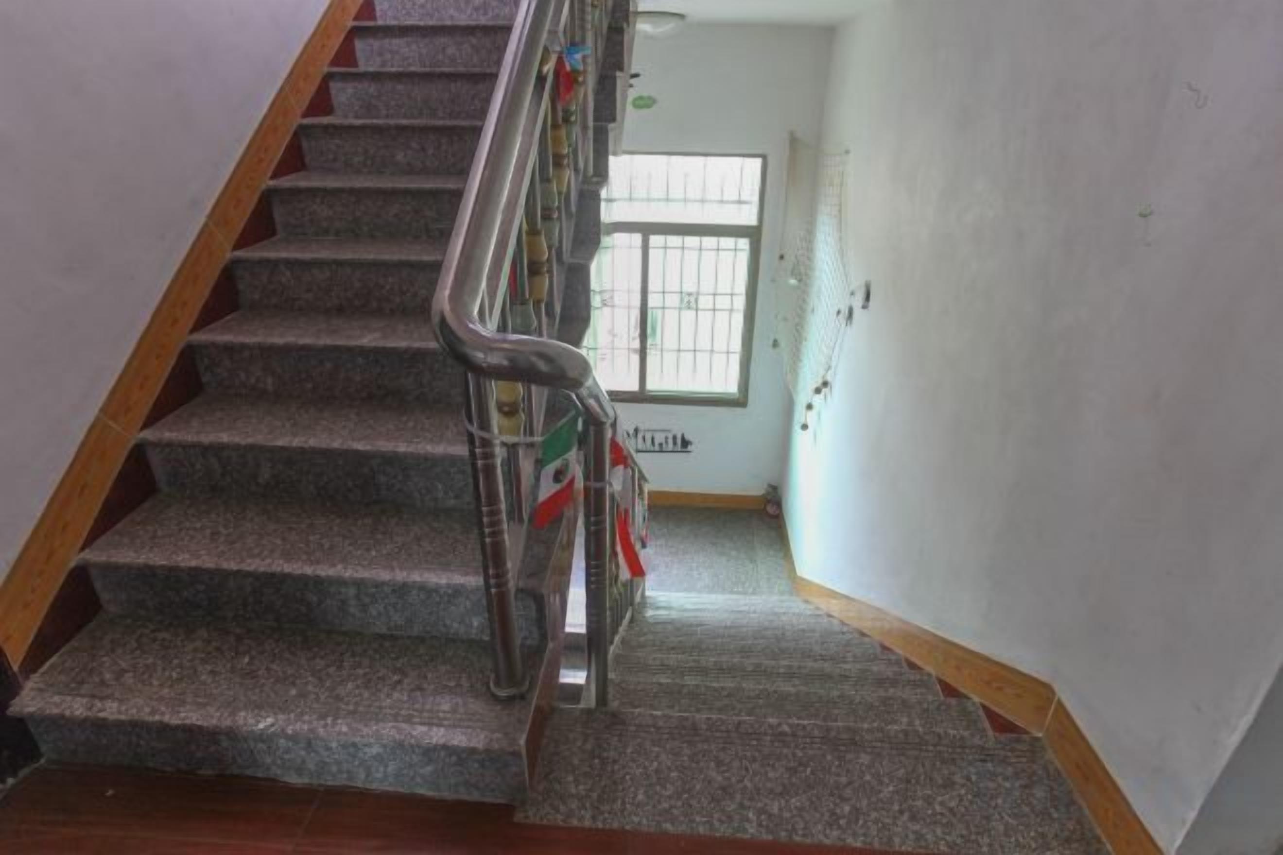 Una escalera con barandilla de metal, escalones alfombrados y barandilla de madera a la izquierda.
