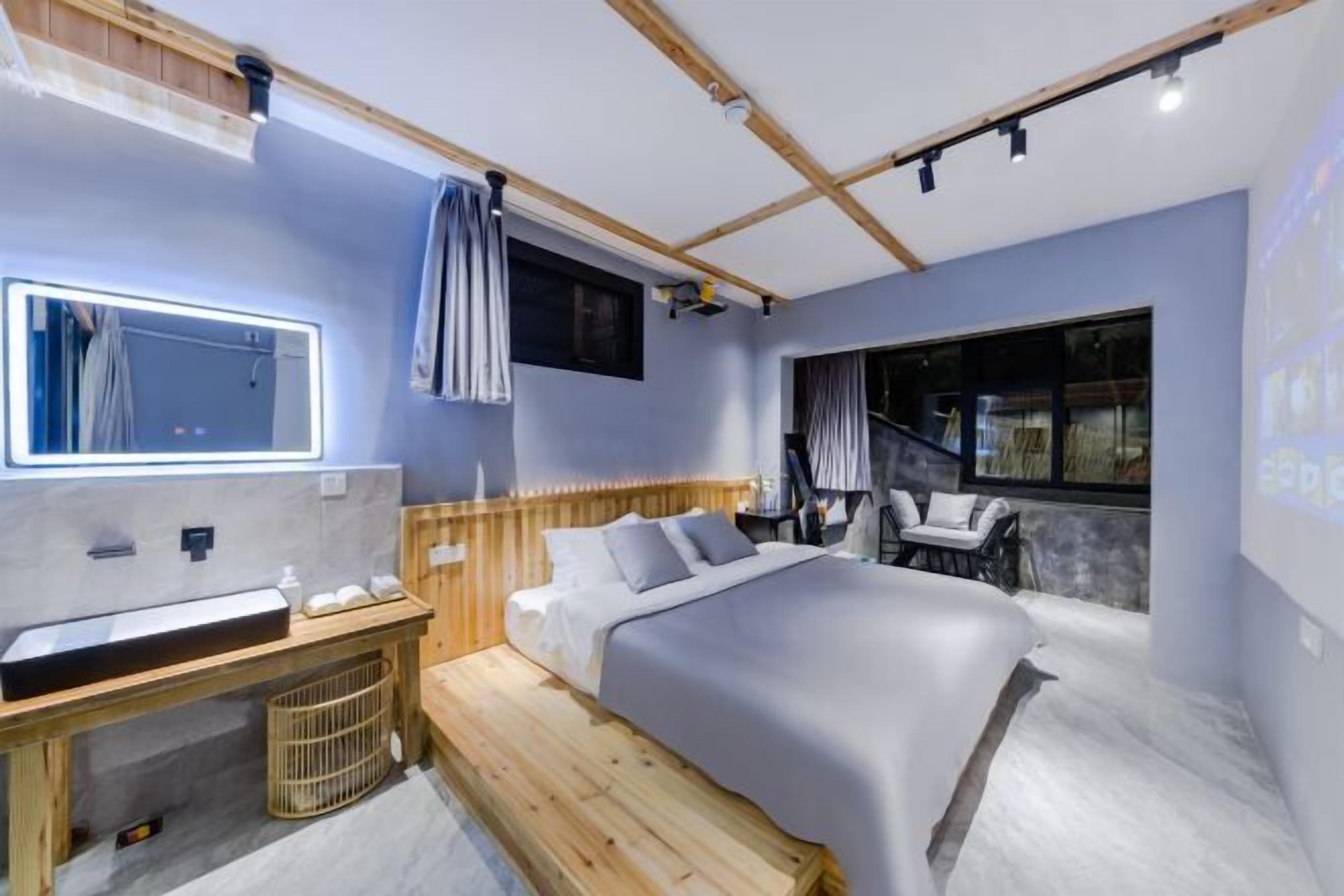 Un dormitorio con cama, mesita de noche, espejo, ventana y vistas al exterior.